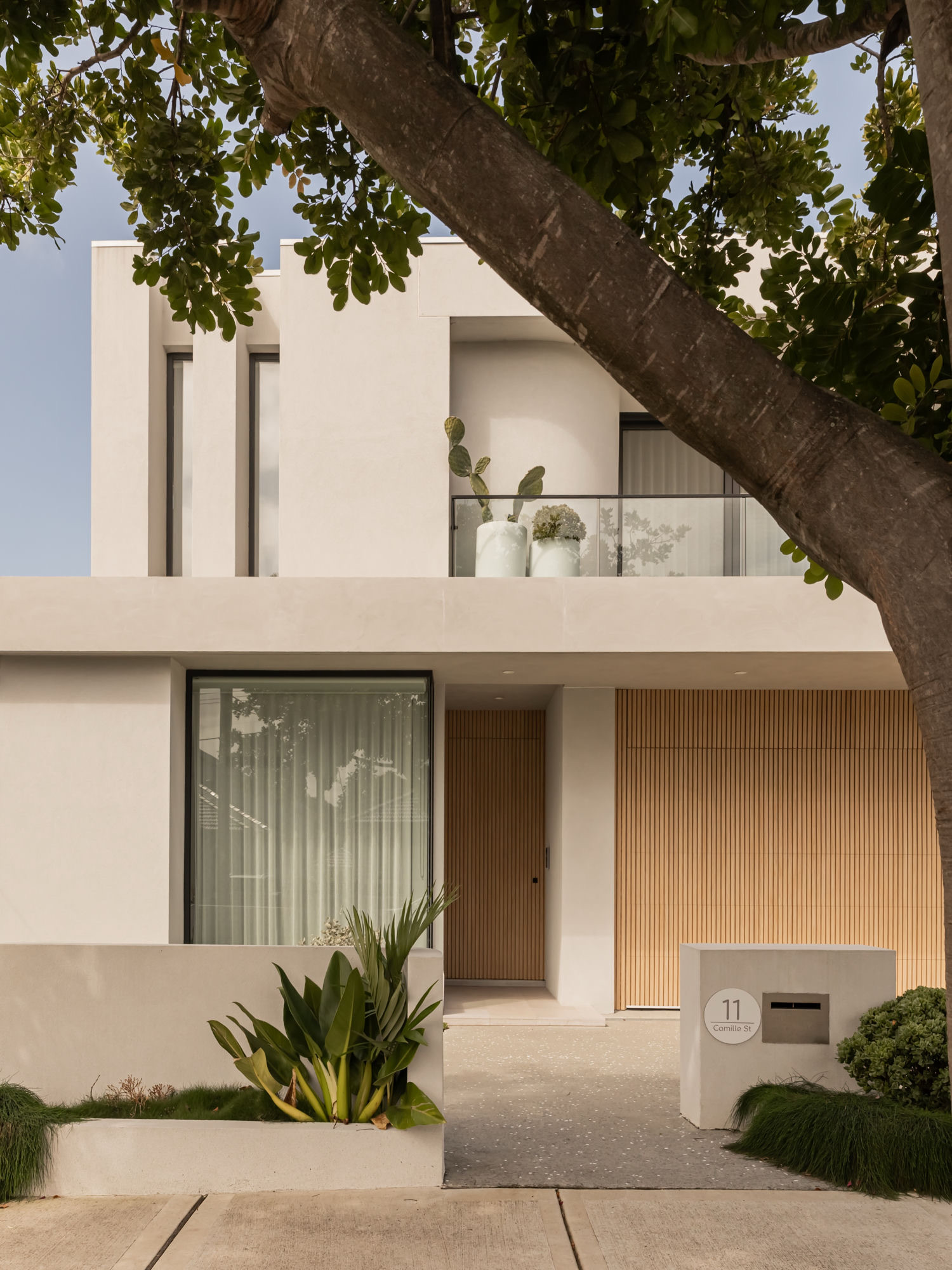 Entry facade with battened timber door and garage below a rendered upper level