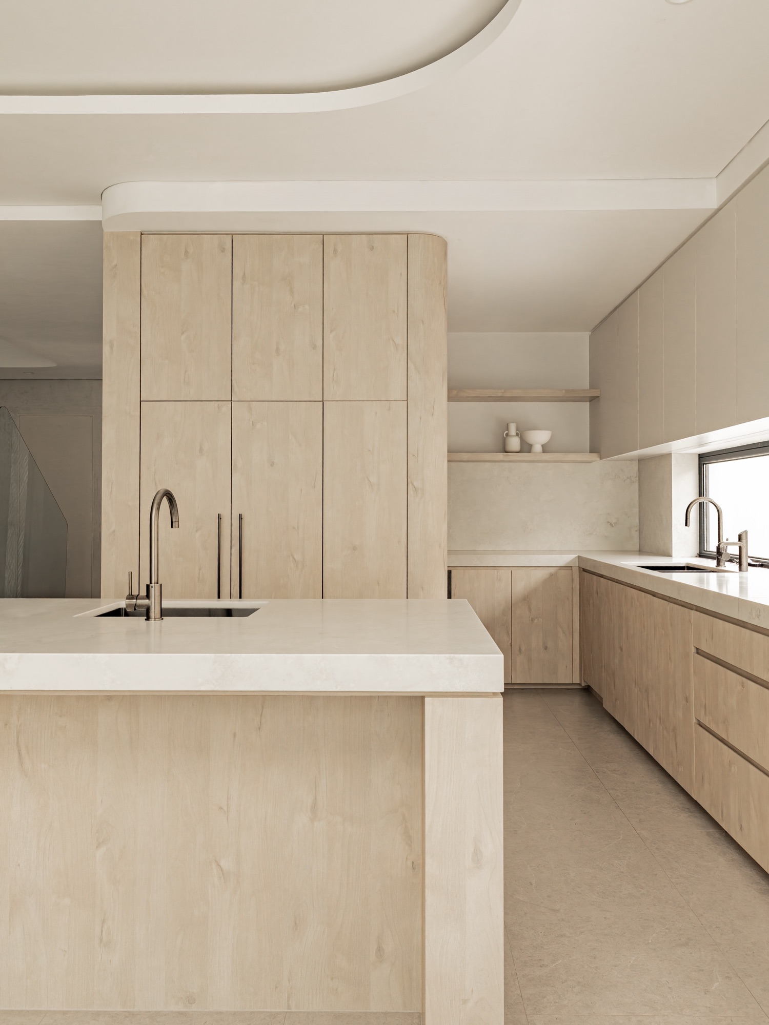 Pale timber kitchen with stone benchtop beneath a curved ceiling